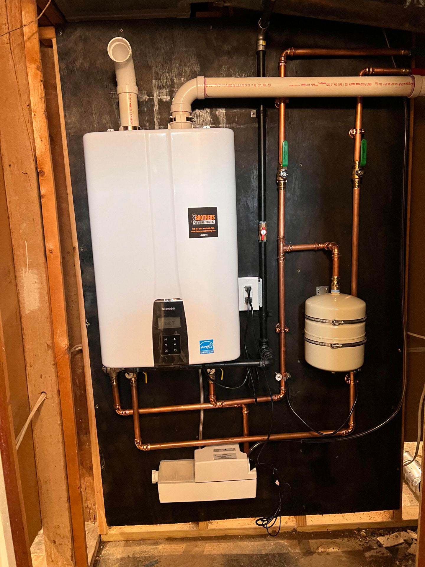 Tankless water heater with copper piping and expansion tank installed in a basement