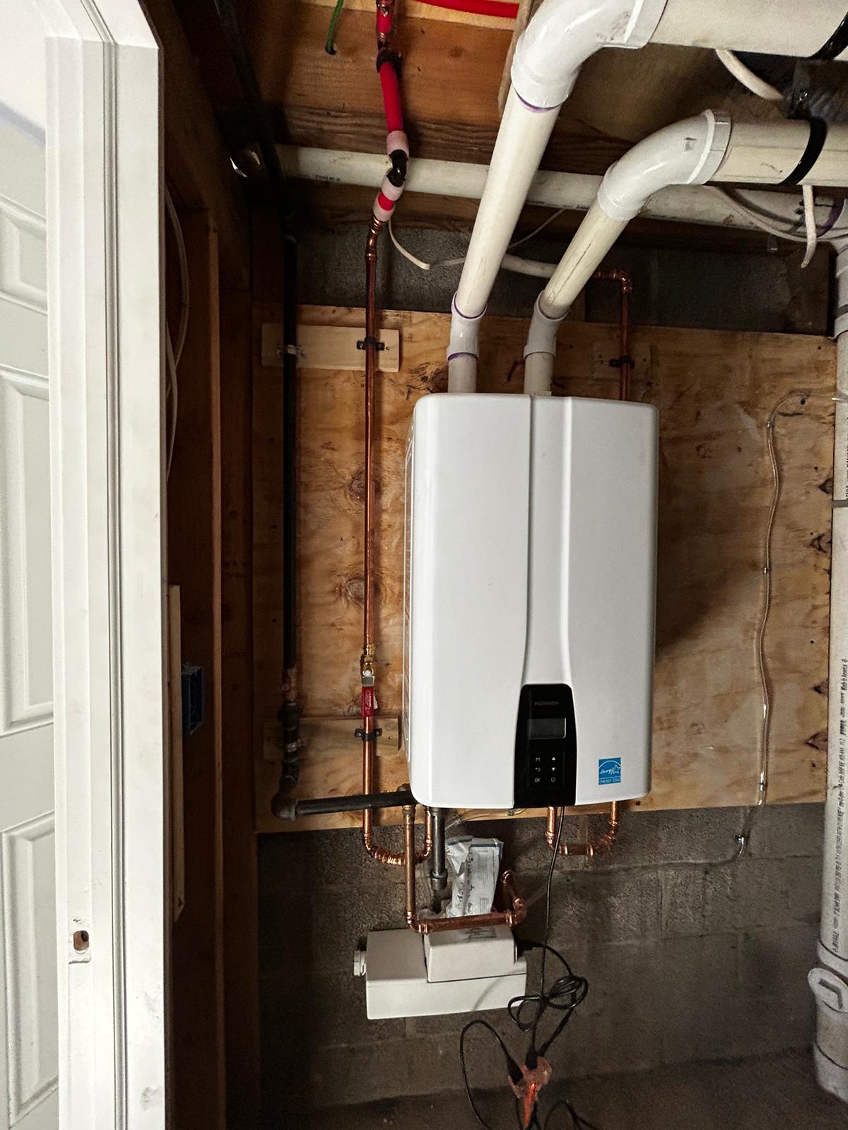 Wall mounted tankless water heater with new copper lines in a utility closet